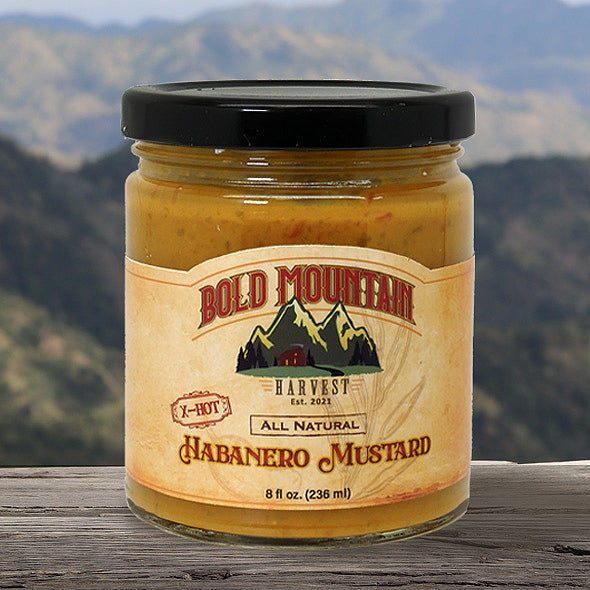 An 8-ounce jar of Habanero Mustard from Bold Mountain Harvest. The mustard is labeled x-hot and is shown in front of a view of mountains.